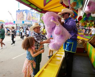 To børn vinder stor lilla bamse i tivoliet ved Calgary Stampede. Foto: Colin Way, Tourism Calgary To børn vinder stor lilla bamse i tivoliet ved Calgary Stampede. Foto: Colin Way, Tourism Calgary