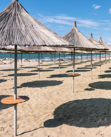 Parasoller på sandstrand i Golem, Albanien