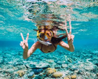 Undervandsbillede af snorklende pige, som svømmer i Australien