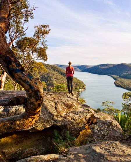 Kvinde på vandtretur i Australien kigger ud over flod fra viewpoint i naturskønne omgivelser