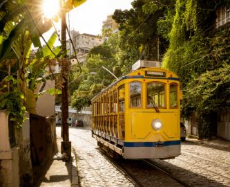 Fin gul sporvogn i solbeskinnet, frodig gade i Santa Teresa-området i Rio de Janeiro i Brasilien