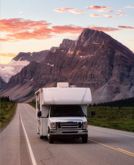 Autocamper på vej i Canada ved skumringstid med Rocky Mountains i baggrunden