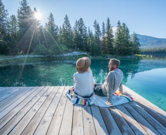 Par sidder på bro i Canada med udsigt til meget blank sø