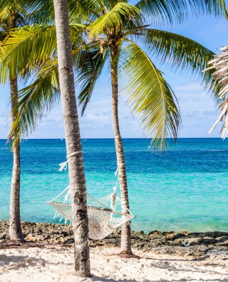 Den tropiske strand Playa Guardalavaca på Cuba med palmer, hængekøje og turkist hav