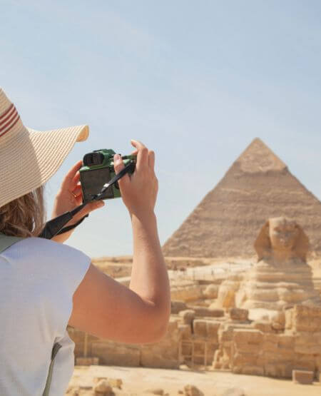 Kvinde, der tager billede af Sfinksen og pyramiderne i Giza, Egypten