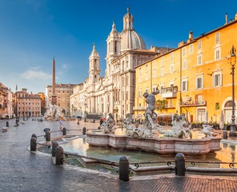 Piazza Navona i Rom med barokke springvand, den imponerende kirke Sant’Agnese in Agone og farverige bygninger i solskin.