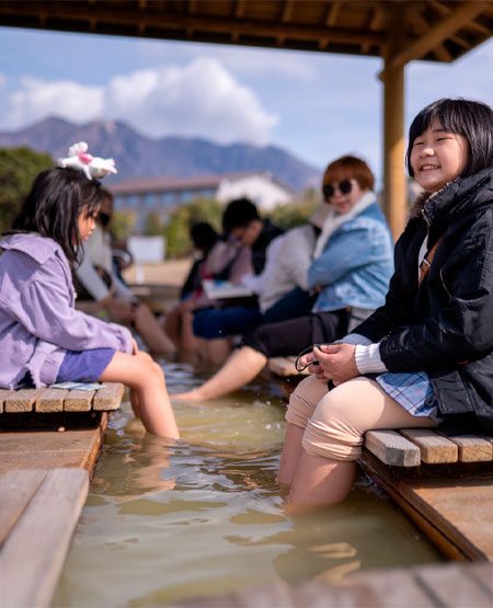 Lokale nyder et køligt fodbad i Shiroyama Park i Kagoshima med udsigt til Sakurajima vulkanen Lokale nyder et køligt fodbad i Shiroyama Park i Kagoshima med udsigt til Sakurajima vulkanen