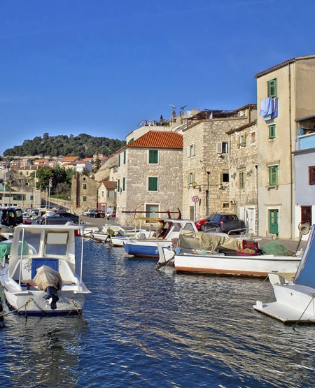 Hyggelig stemningsbillede af bygninger og kanal med både i Sibenik, Kroatien