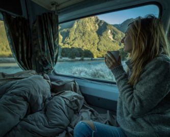 Kvinde drikker kaffe i autocamper med udsigt til New Zealands natur