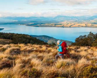 Vandrende kvinde med rød rygsæk i New Zealand