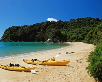 Gule kajakker på blød sandstrand i Abel Tasman National Park