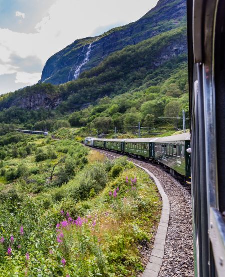 Flåmsbanen i Norge med udsigt til fjelde og vandfald Flåmsbanen i Norge med udsigt til fjelde og vandfald