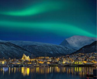Udsigt over Tromsø om aftenen med sne, fjelde og nordlys