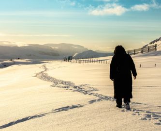 Kvinde går i snelandskab med lav vintersol i Hammerfest