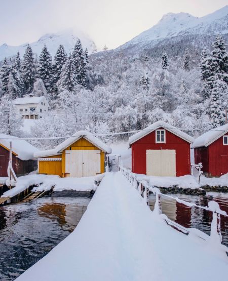 Bådbro i Søbo med udsigt til træhuse, fjelde og vinterlandskab