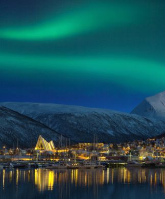 Nordlys over Tromsø by med sneklædte fjelde i baggrunden