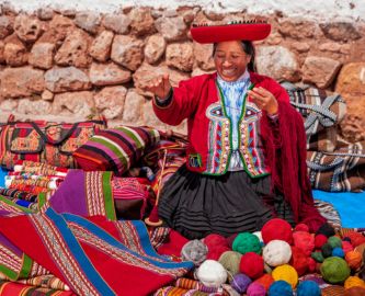 Smilende kvinde i Peru, der laver flotte, farverige tekstiler