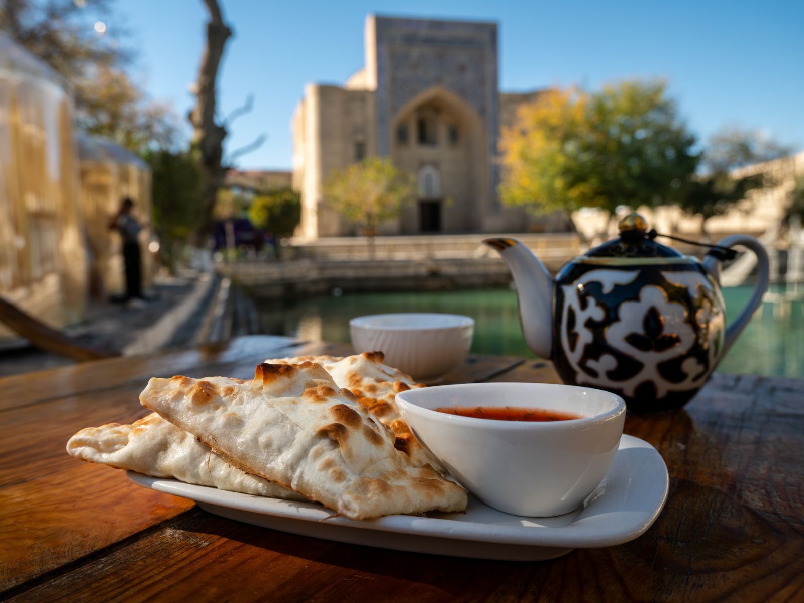 Te, samsa og tomat med Bolo Haouz-moskeen i Bukhara i baggrunden, Usbekistan Te, samsa og tomat med Bolo Haouz-moskeen i Bukhara i baggrunden, Usbekistan