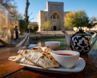 Cafebord i Usbekistan - med te og brød og madrasah i baggrunden