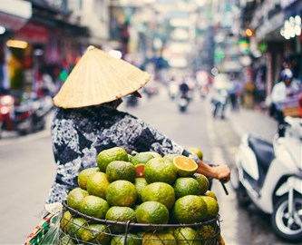 Vietnameser på knallert med frugt på gaden