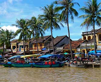 Smuk havn med både og palmer og huse i Hoi An i Vietnam