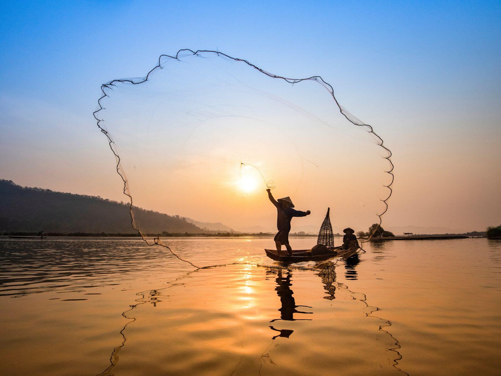 Vietnameser, der kaster fiskenet på Mekong-floden i solopgang, Vietnam