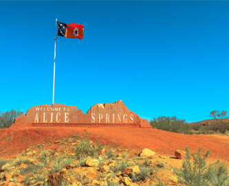 Alice Springs velkommen skilt udsigt med flag og blå himmel