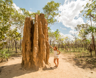 Dame stående op af et kæmpe termitbo i nationalparken Litchfield, Darwin, Australien