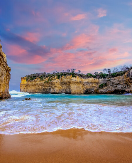 Flot solnedgang ved strand med klipper i Victoria, Australien