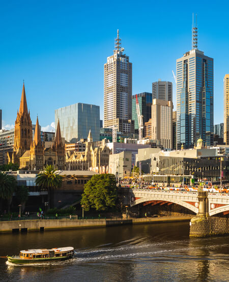 Melbourne skyline i solskin med bro og vand foran