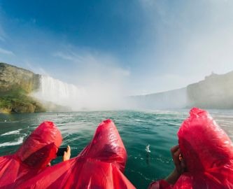 Tre mennesker i røde regnslag på sejltur ved Horseshoe Falls, NIagara Falls