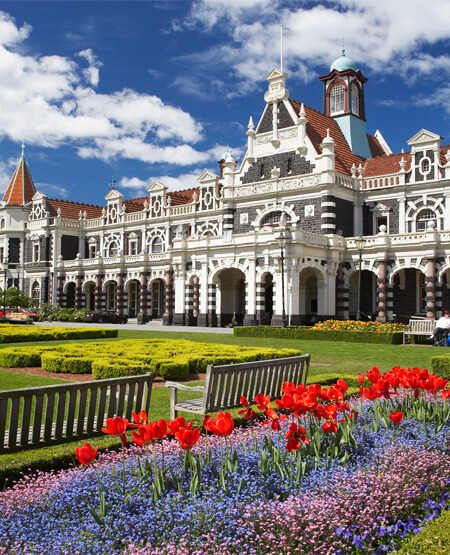 Dunedin Railway Station med farverige blomster i forgrunden