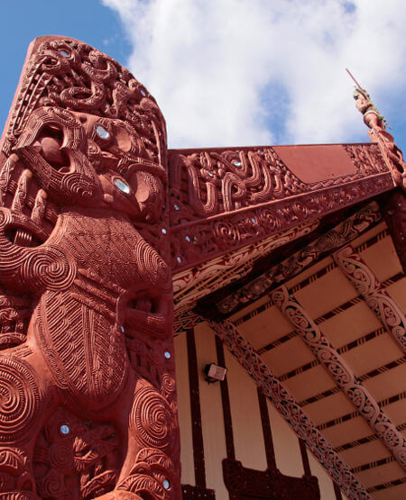Traditionelle træudskæringer på maori-følleshus i Rotorua