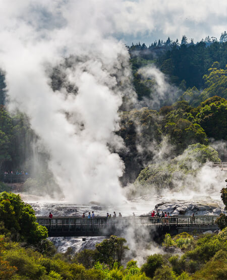 Turister ppå bro omgivet af svovldampe i Rotorua
