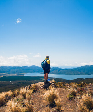 Vandrer med rygsæk og smuk udsigt over New Zealands landskab i Tongariro