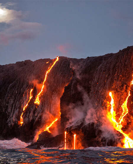 Glødende lava der flyder ud i det mørke hav på Big Island, Hawaii