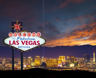 Las Vegas skilt i aftenbeslydning med oplyst by i baggrunden