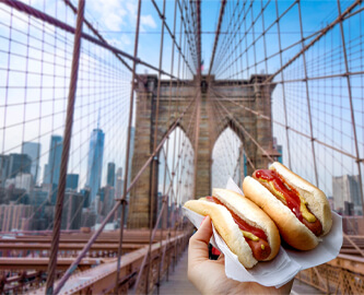 To hotdogs med udsigt til New York skyline og bro i baggrunden