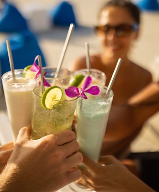 Venner som skåler i farverige drinks i Beach Club i Seminyak på Bali