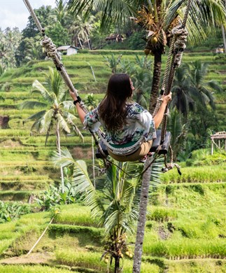 Kvinde der gynger højt over risterrasserne ved Ubud på Bali