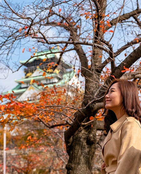 Osaka slottet med japansk kvinde gående foran