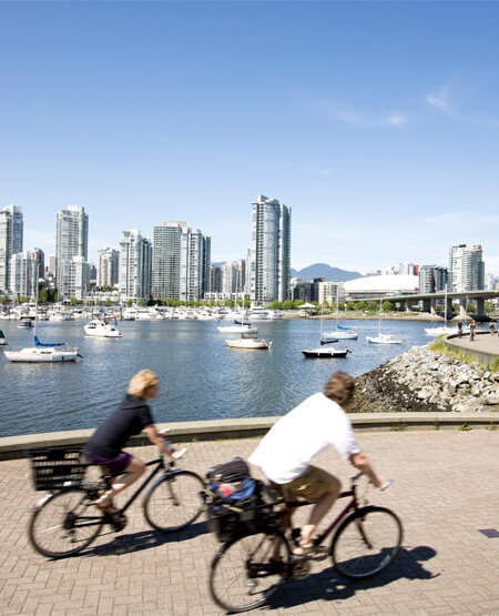Folk på cykeltur med Vancouvers bygninger i baggrunden