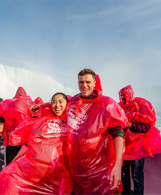 Glade mennesker i røde regnslag klar til sejltur med katamaran til Niagara Falls